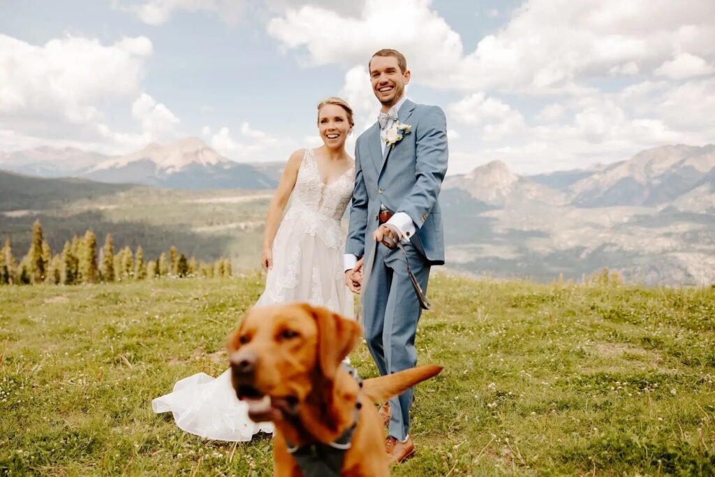 Bride hugging her dog with mountain peaks behind them